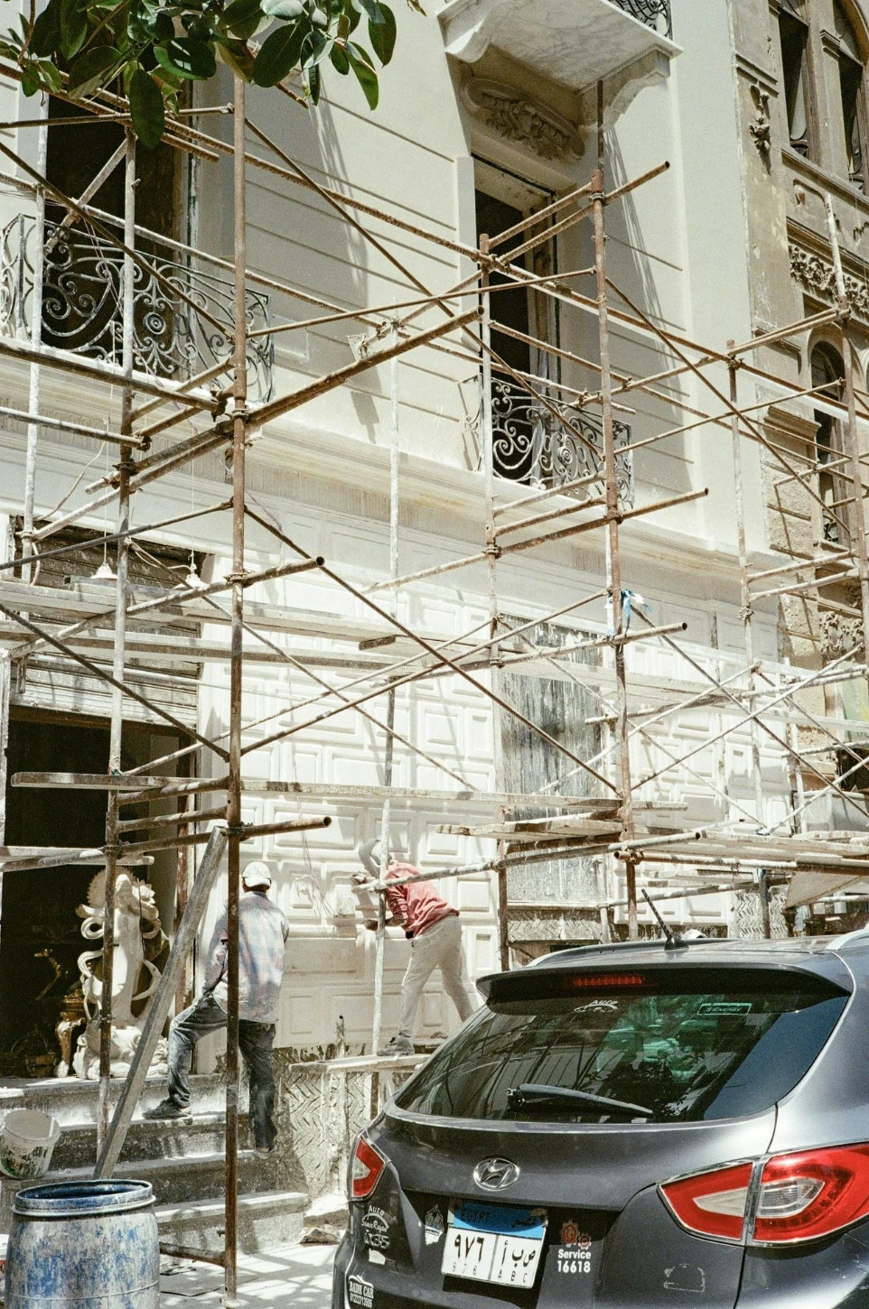A car parked in front of a building under scaffolding